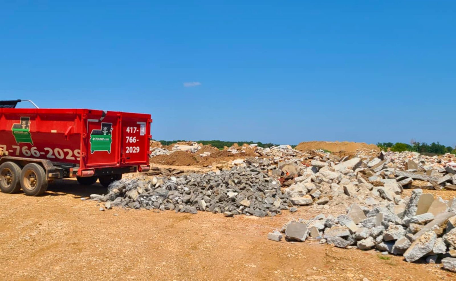 Red roll-off dumpster on a dirt lot at a new construction site