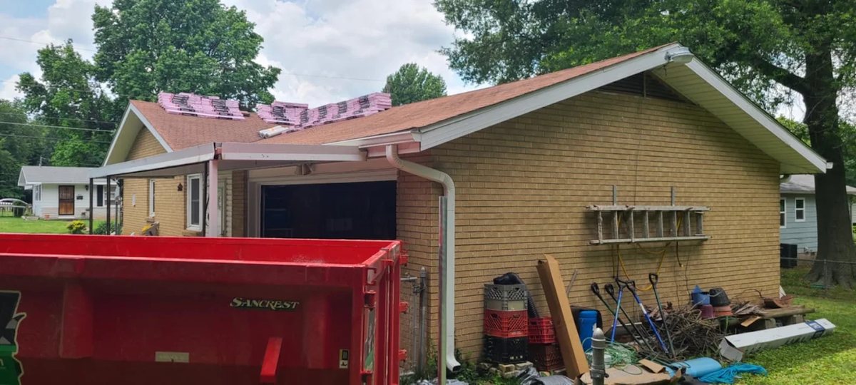 A red 417 Dumpster Rental roll-off set beside a house during a roof tear-off in Springfield, MO