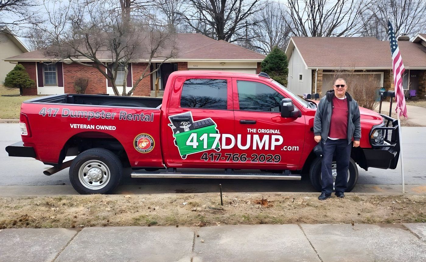 A 417 Dumpster Rental pickup flying an American flag, with the driver standing beside it.
