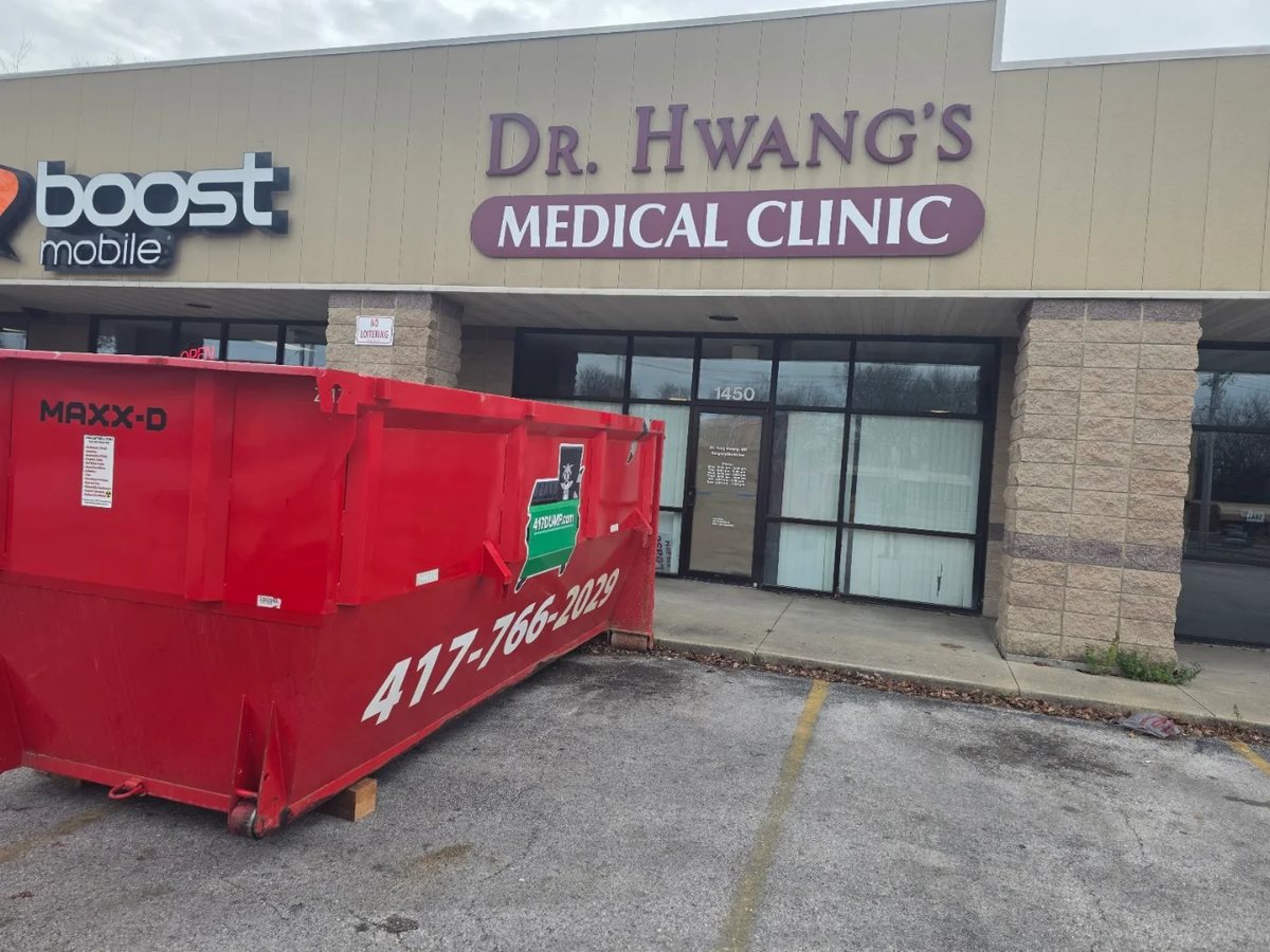 Red roll-off dumpster set outside a Springfield medical clinic storefront