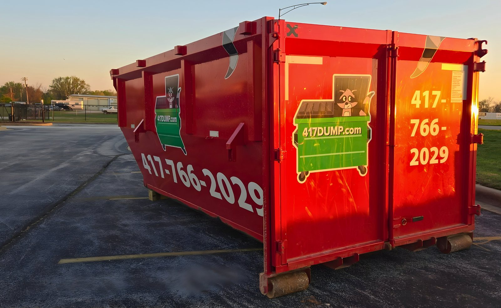 Red 417 Dumpster Rental roll-off dumpster sitting in a parking lot during the day.