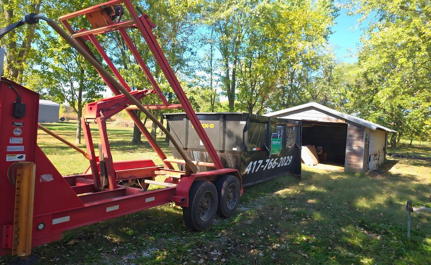The red roll-off dumpster set down flat on the driveway, ready to load.