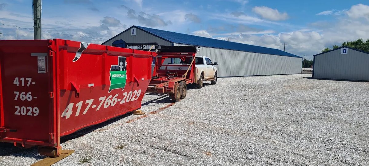 Gooseneck trailers and roll-off dumpsters lined up in the 417 Dumpster Rental shop yard.