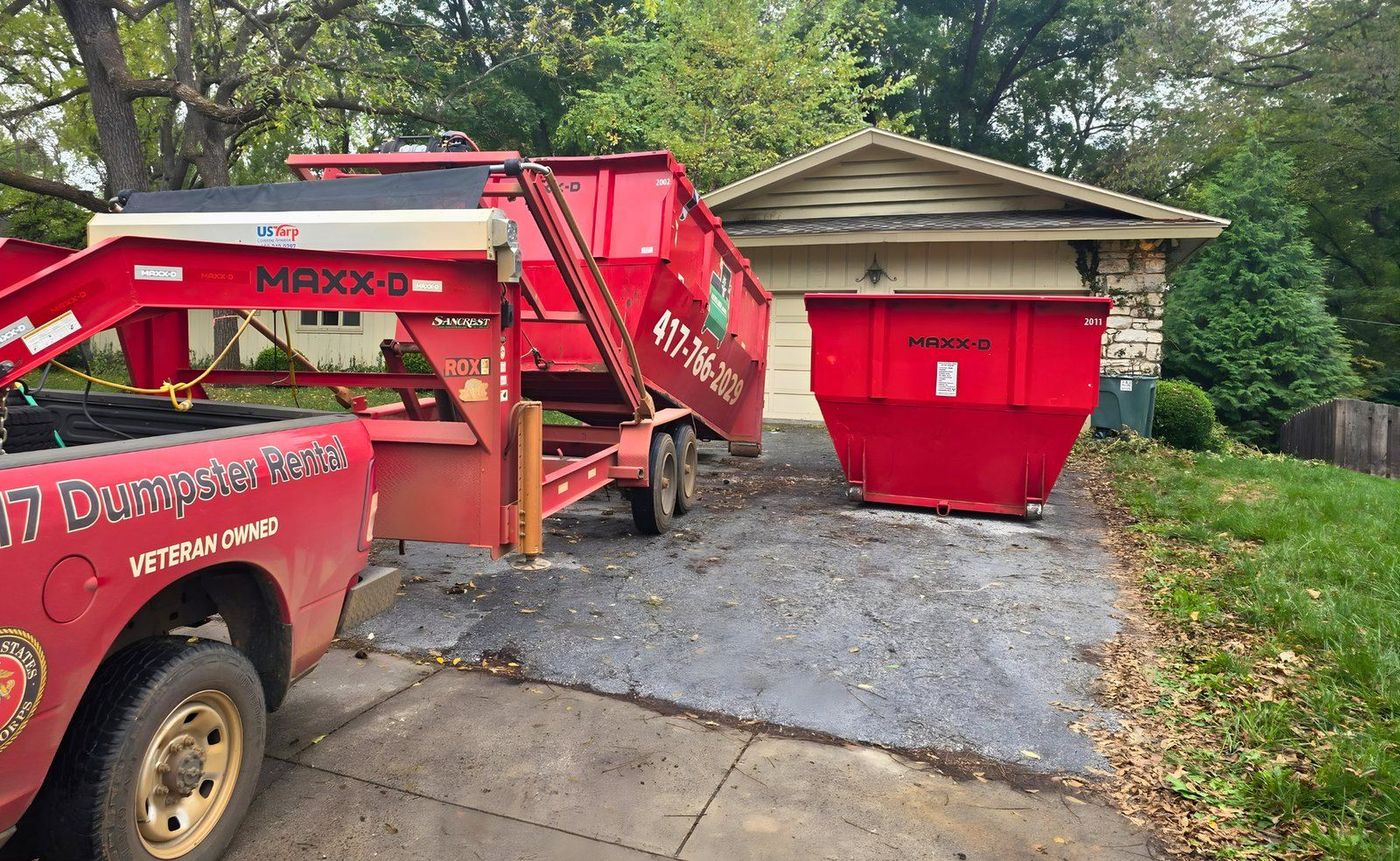 A 417 Dumpster Rental truck and trailer delivering a roll-off dumpster at a Springfield, MO house